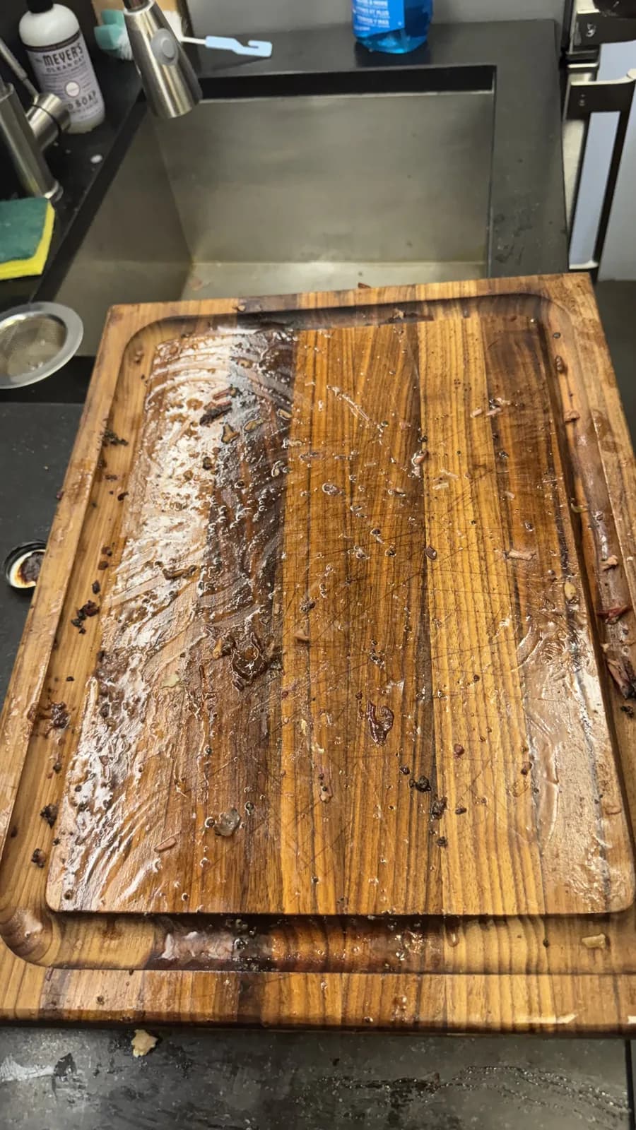 An empty wooden serving board with only scraps and knife marks left.