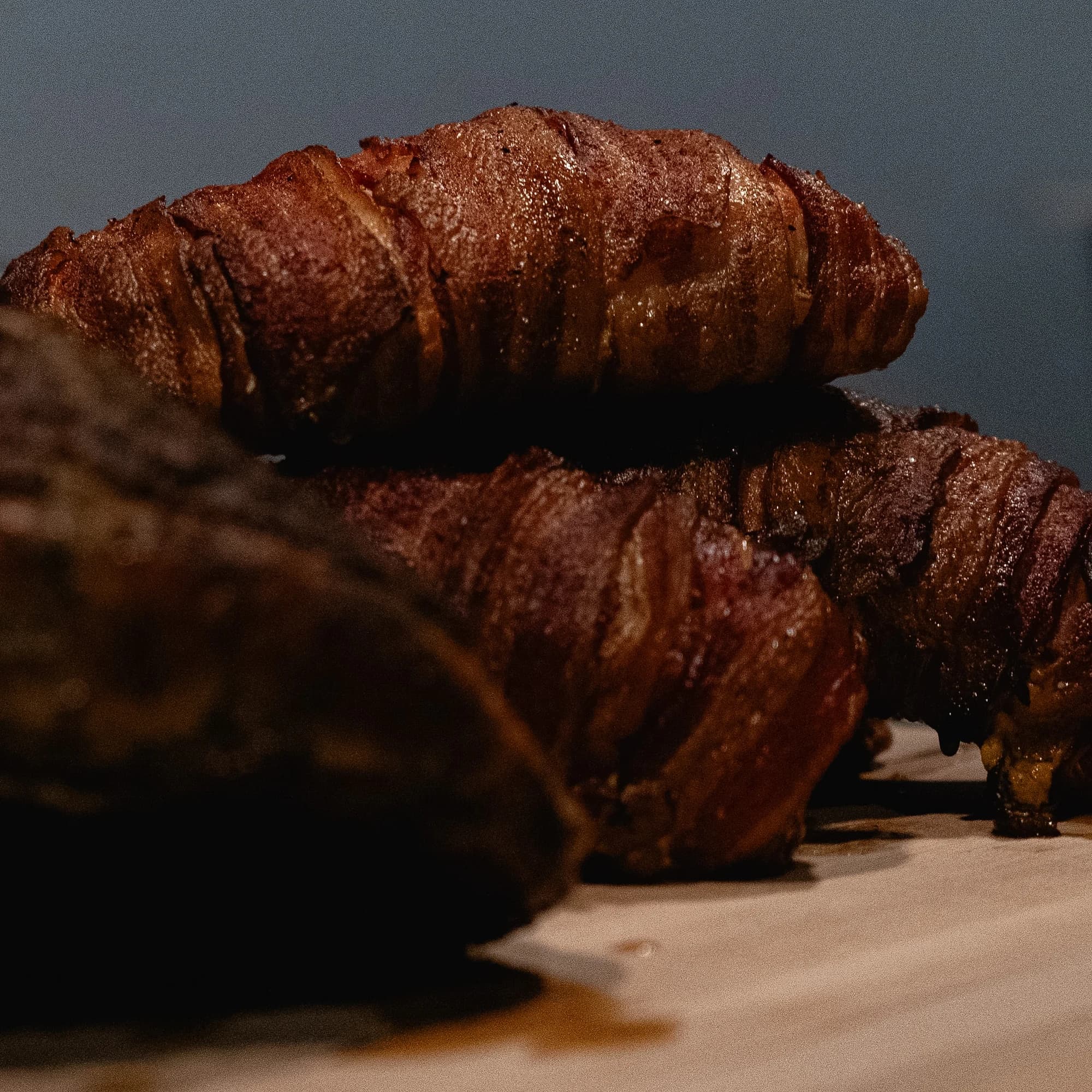 Bacon-wrapped stuffed chicken portions lined up on a cutting board.