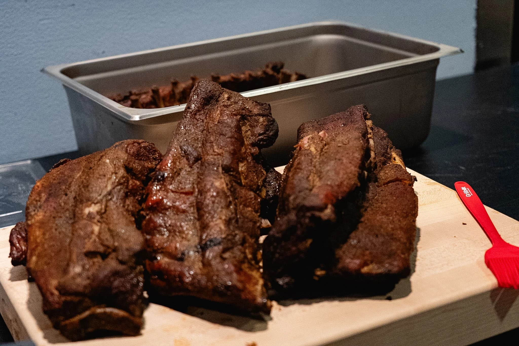 Wide view of several smoked pork rib sections on a cutting board.