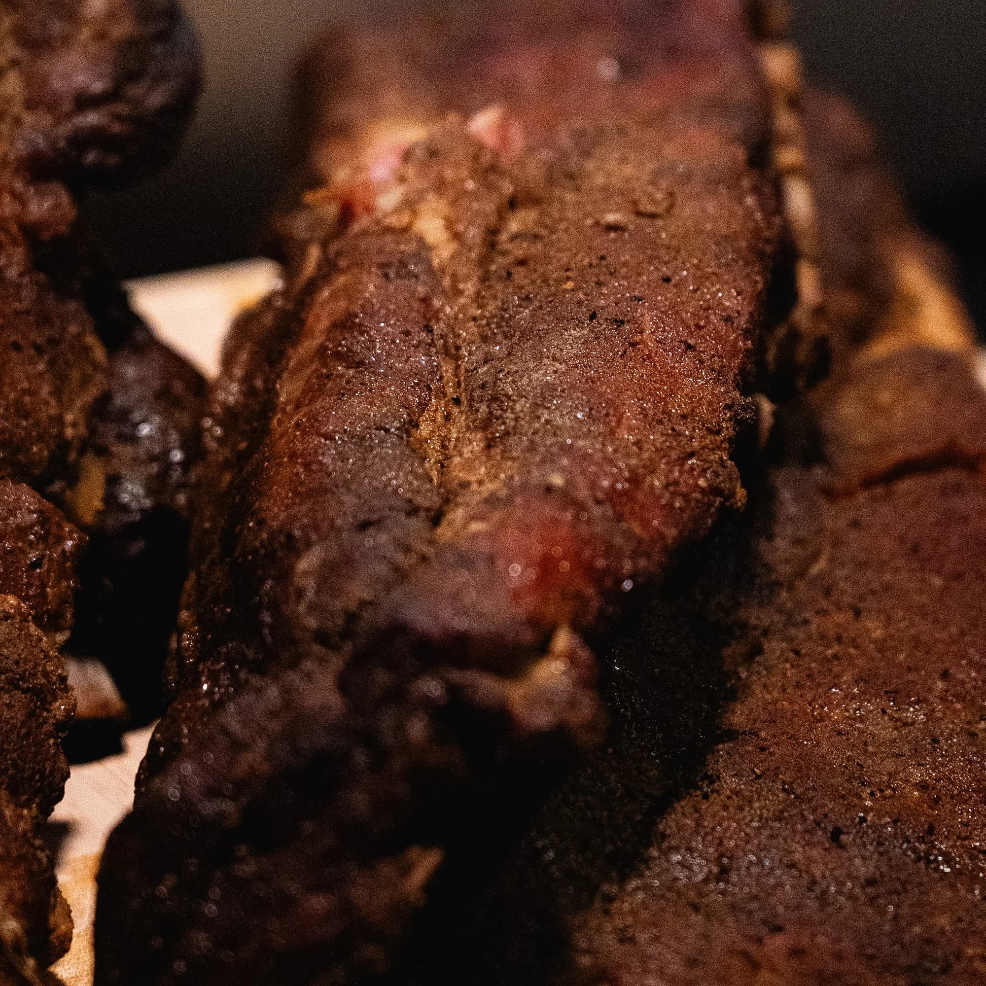 Tight detail of a smoked pork rib section resting among the finished ribs.