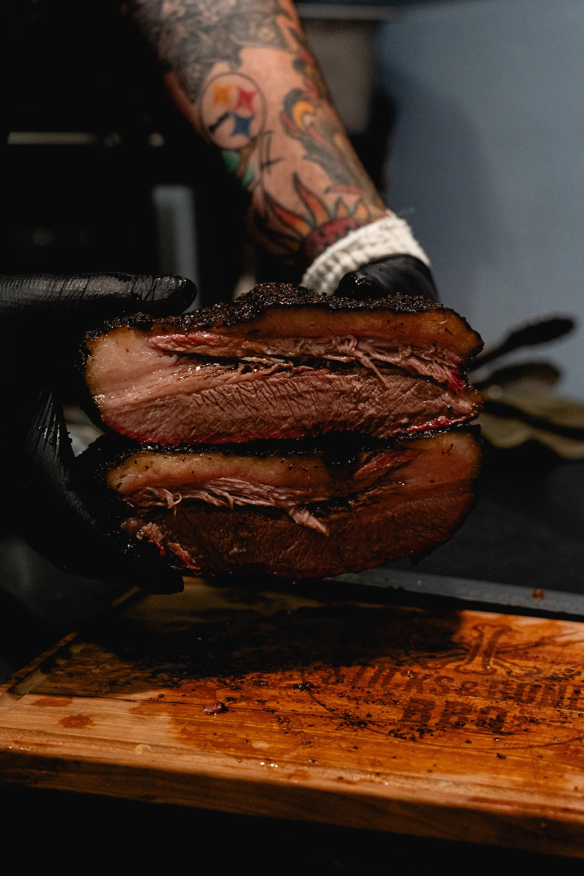 A second view of the sliced brisket held above the carving board.