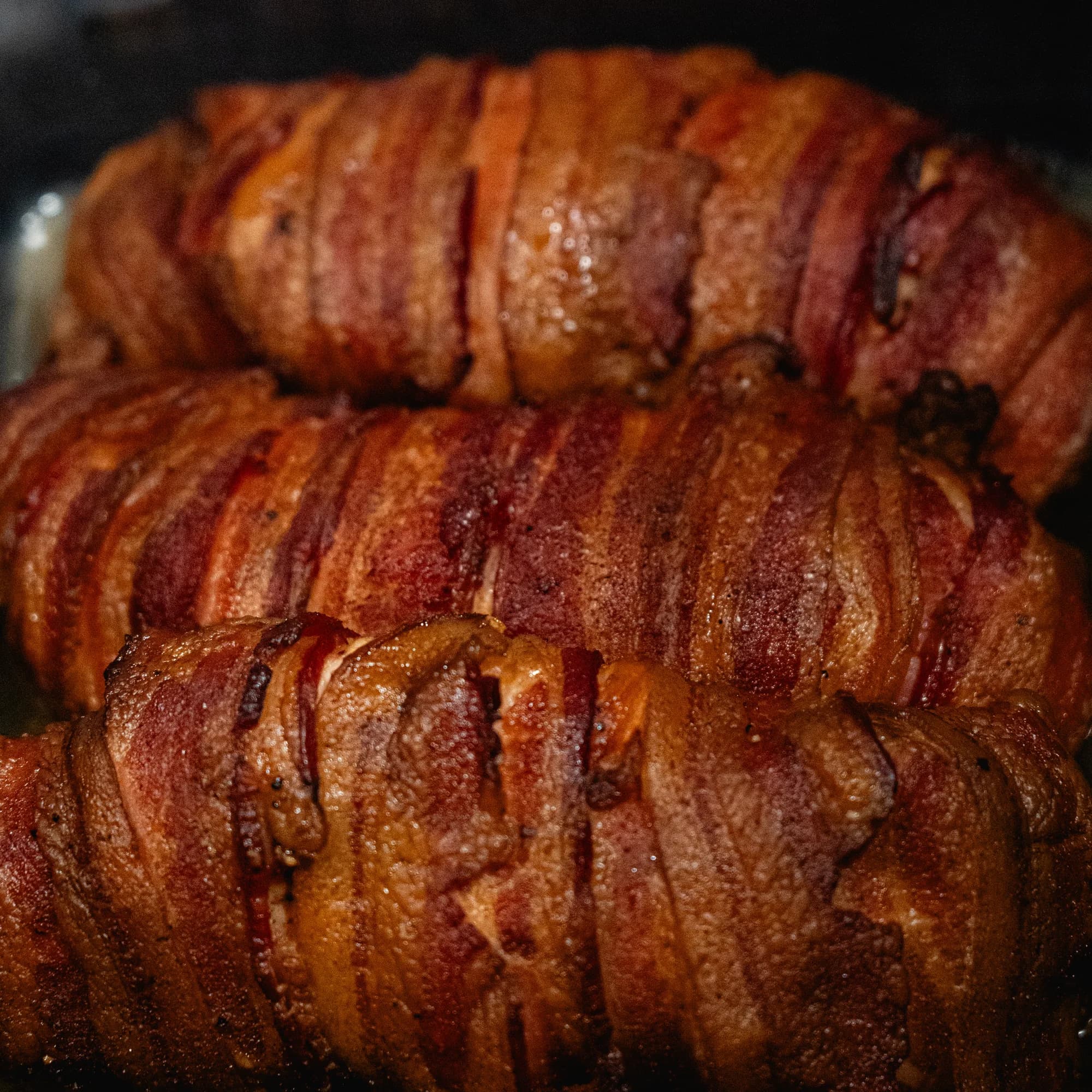Bacon-wrapped stuffed chicken breasts stacked after smoking.