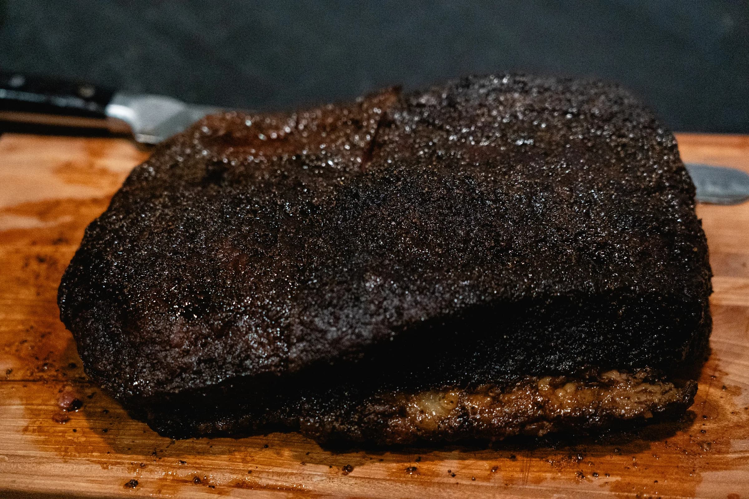 A whole smoked brisket with dark bark resting on a carving board.