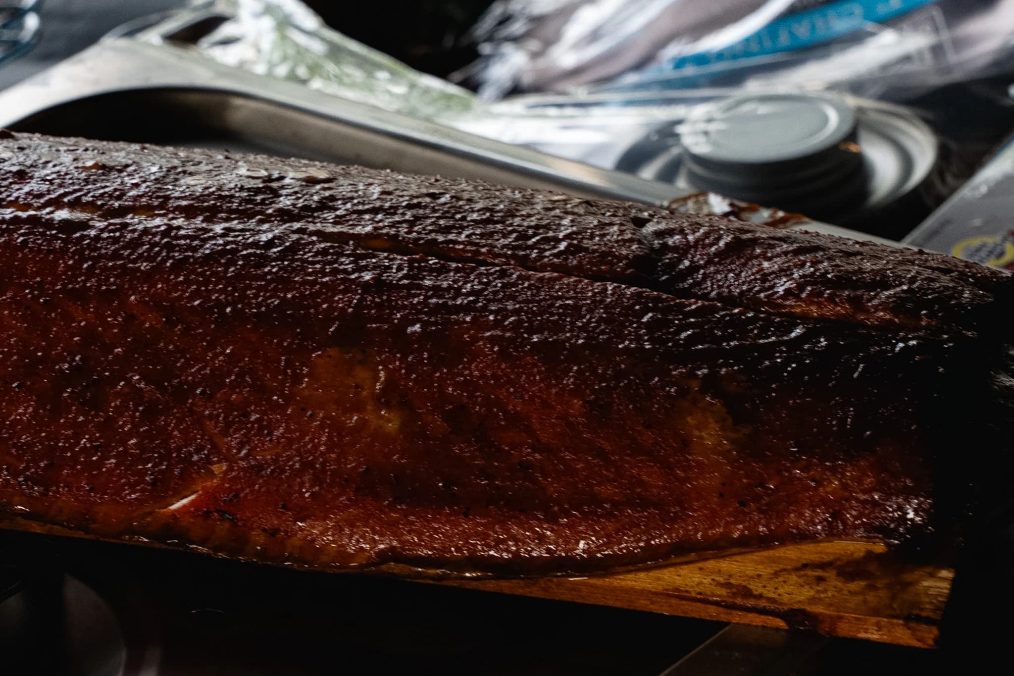 A glazed side of smoked salmon resting on a cedar plank.